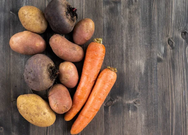 Zanahorias, patatas y remolachas sobre un fondo de madera gris oscuro — Foto de Stock