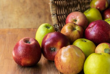 Hasır sepetten dökülen kırmızı ve yeşil elmalar.