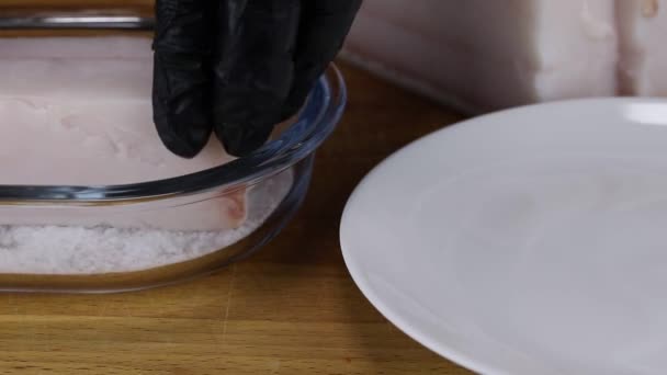 The chef soaks in salt a large piece of pork fat and puts it on a white plate — Stock Footage Chef Soaks Salt Large Piece Pork Fat Puts White Plate Royalty Free Stock Footage