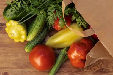 Green, red and yellow vegetables fell out of a paper bag