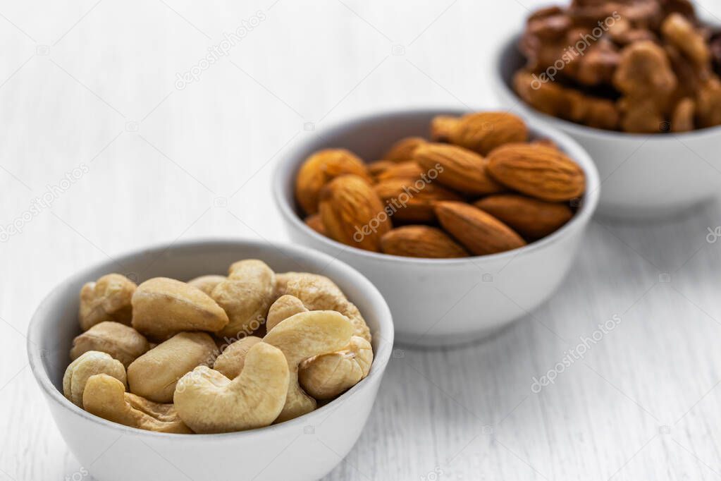 Cashews, almonds and walnuts in white glass bowls