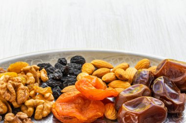 Kurumuş meyveler ve fındıklar gümüş tepside duruyor.