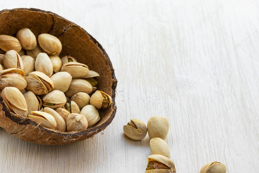 Pistachios lie in half a coconut shell