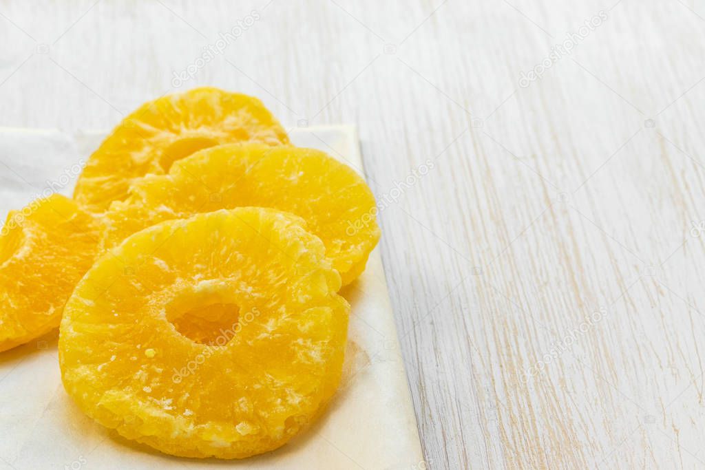 Slices of dried pineapple lie on a food paper