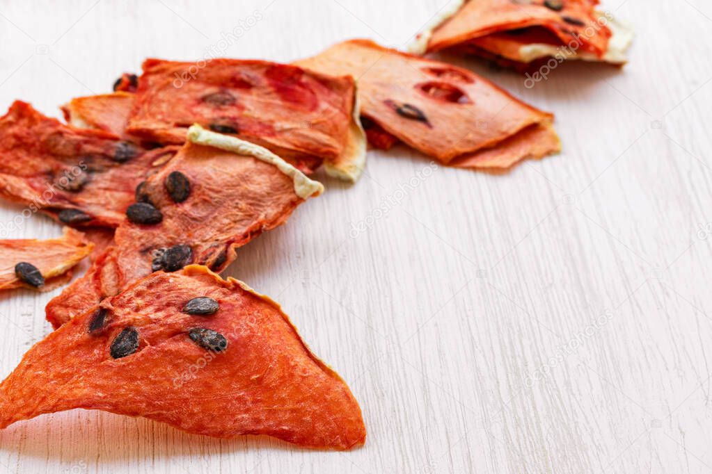 Dried watermelon chips lie on a white background