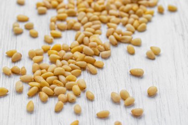 Çam fıstıkları beyaz ahşap bir yüzeye saçılmış.