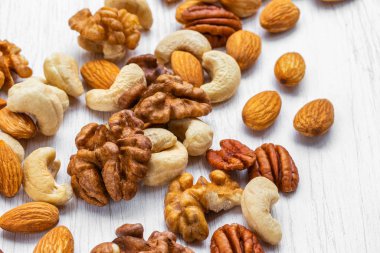 Beyaz ahşap bir yüzeye saçılmış çeşitli fındıklar.