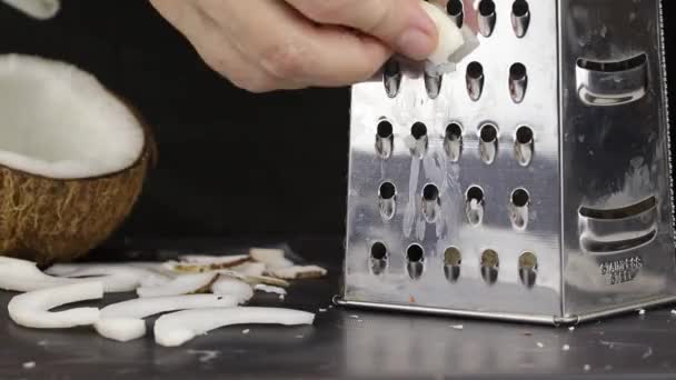 Ręka Samicy Pociera Kawałek Kokosa Metalową Tarkę Aby Uzyskać Posiekane — Wideo stockowe