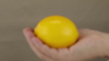 Kamera, bulanıklıktan odak noktasına limonla yaklaşan bir kadın eli gösteriyor.