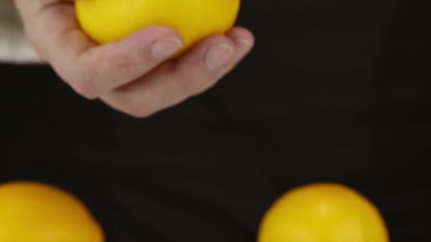 女性の手は3つのレモンのうちの1つを背景に取り それを前景に持ってきて クローズアップ — ストック動画