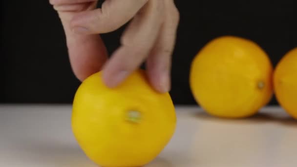Main féminine tord un citron plusieurs fois sur une table blanche, gros plan 