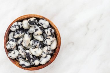 Black beans covered with salt lie in a brown bowl