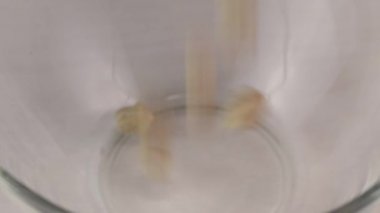 Nohut çekirdekleri cam şeffaf bir kaseye düşer, yakın plan.