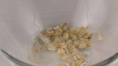 Yulaf ezmesi cam şeffaf bir kaseye dökülüyor, yakın plan.