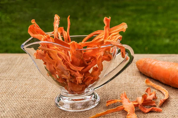 Овочеві Морквяні Чіпси Лежать Скляній Прозорій Вазі Сірому Мішку Фоні Ліцензійні Стокові Зображення