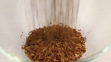 Anlık ve doğal öğütülmüş kahvenin karışımı şeffaf cam bir kâseye dökülür. Yakın plan.