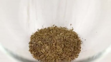 Dill tohumları şeffaf cam bir kaseye düşer, yakın plan.