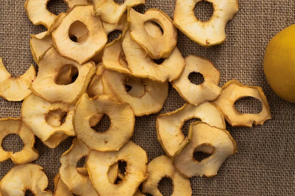 yellow apple chips scattered on light brown burlap next to a yellow apple
