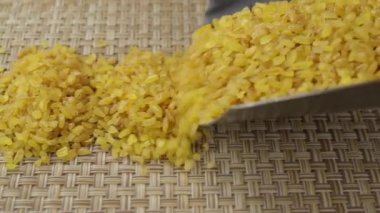 Krupa bulgur bir metal kepçesinden düşüyor, yakın plan.