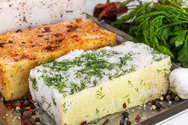 İki büyük parça kırmızı biberli tuzlanmış domuz yağı, metal tepside bir biber ve dereotu karışımı bulunur.