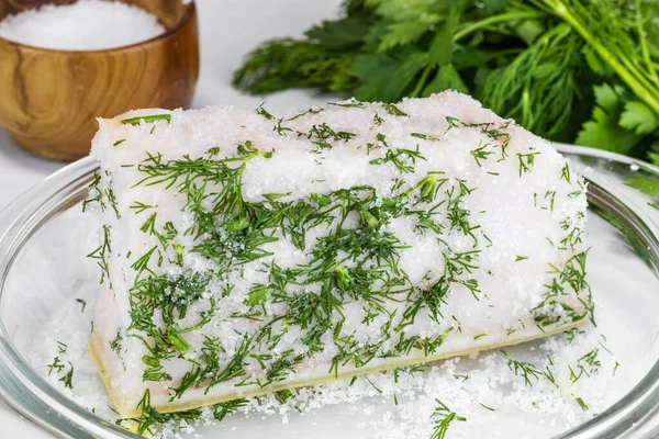 Dereotlu büyük bir parça tuzlanmış yağ oval cam bir kasede yatıyor.