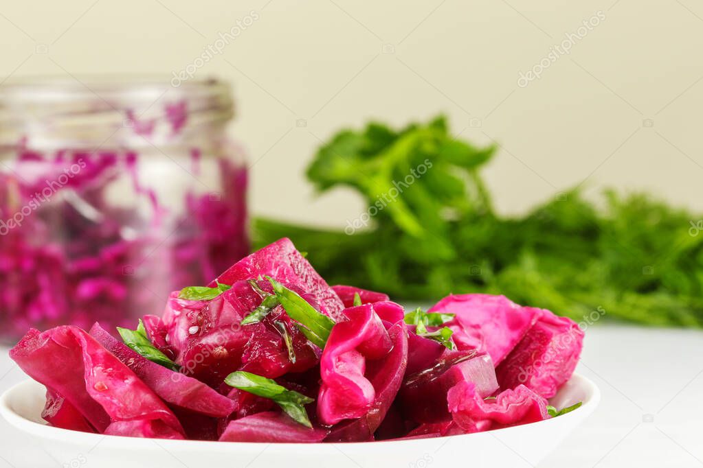 Fermented cabbage with beets lies on a white plate, side view, close-up