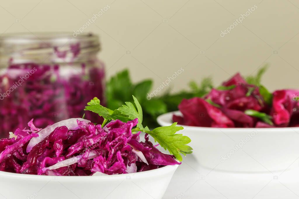 Fermented red cabbage lies on a white plate, side view, close-up