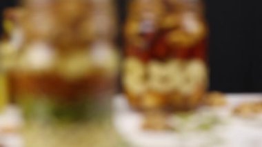 Bulanıklıktan, fındık, tohum ve bal karışımlı iki cam kavanoza odaklanma, yakın çekim.