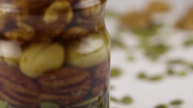 Fındık, tohum ve bal karışımıyla dolu cam bir kavanoz, yakın plan.