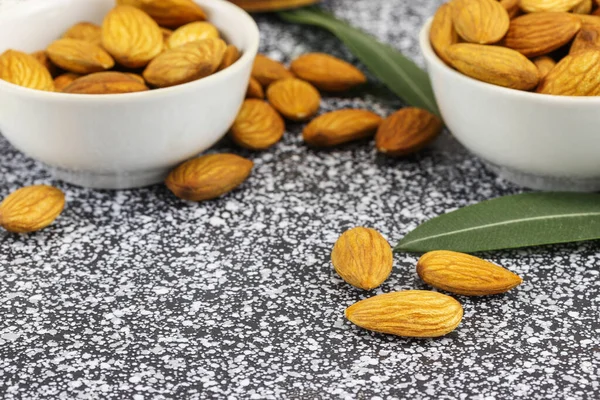 Bademli iki beyaz kase siyah beyaz mermer bir yüzey üzerinde duruyor.