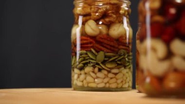 Bala batırılmış fındık ve tohumların bir karışımı, cam kavanozlar saat yönünde döner, yakın plan,