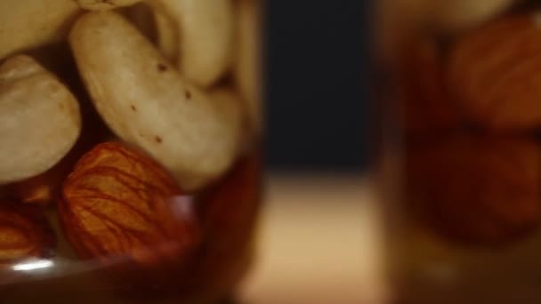 蜜の中にナッツの混合物と3つのガラス瓶が時計回りに回転し サイドビュー 非常にクローズアップ — ストック動画