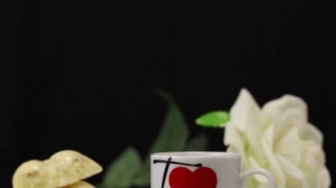 Beyaz gözenekli çikolata beyaz bir yüzeyde, kalp logosu olan beyaz bir kupanın yanında duruyor.