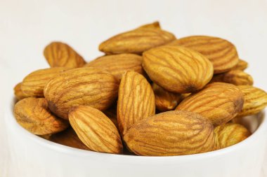 Beyaz arka planda beyaz bir kasede badem, yakın plan.