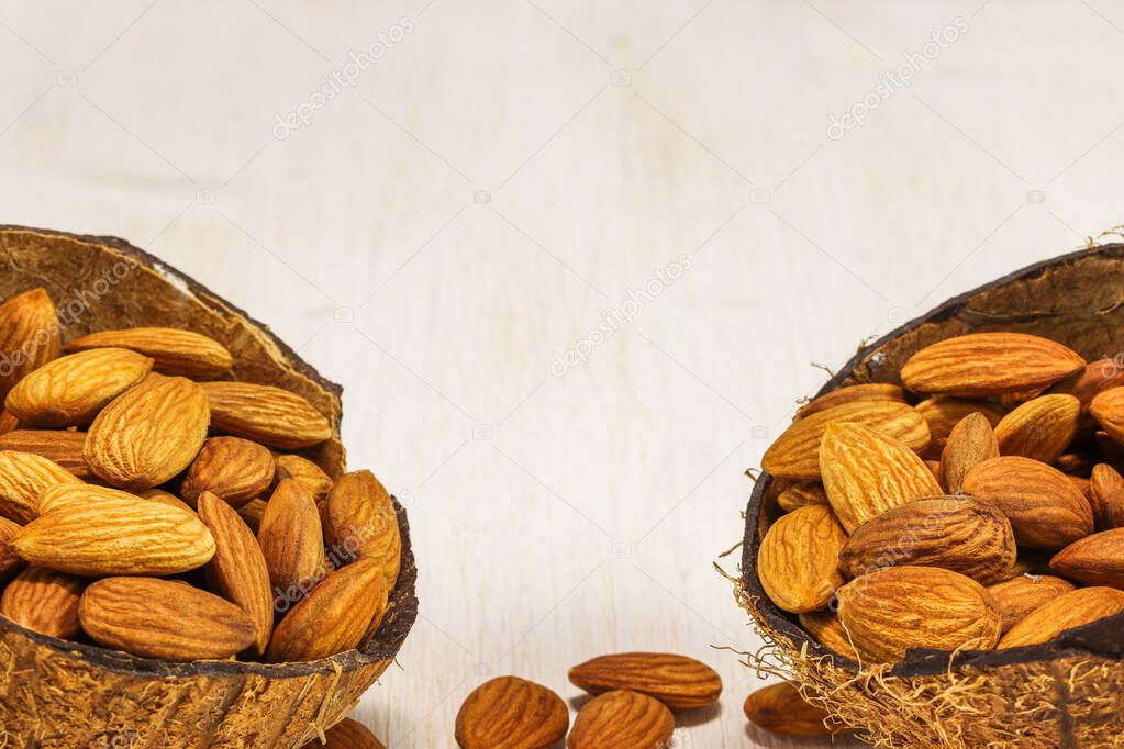 Almond nuts in two half coconut on a white background, close-up