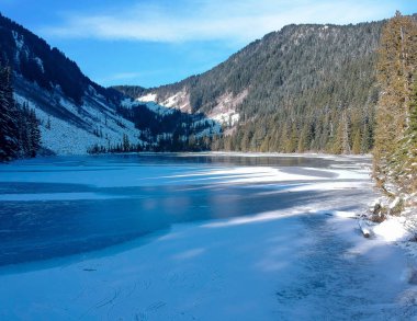 Donmuş olan Talapus Gölü Alp Gölü 'nün vahşi doğasının gölgesi altında. Washington' daki dağ yamacında Cedars ve Hemlock ağaçlarıyla kaplı bir günde..