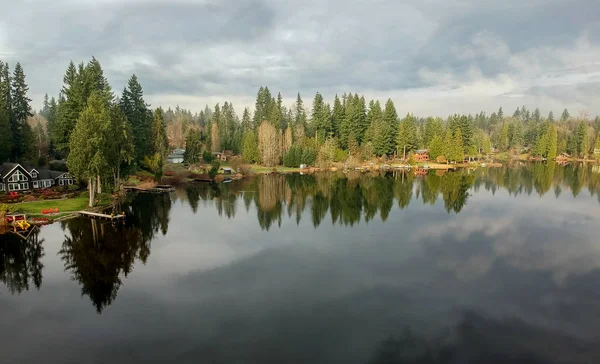 Lovely Lake Joy and the waterfront houses on a fog covered day with the surrounding trees and lingering clouds above reflecting in the water in the pacific northwest.