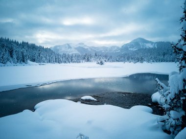 Snow covered frozen beautiful Gold Creek Pond with snow covered trees and trail during the winter in the Alpine Lakes Wilderness in Kittitas county Washington State clipart