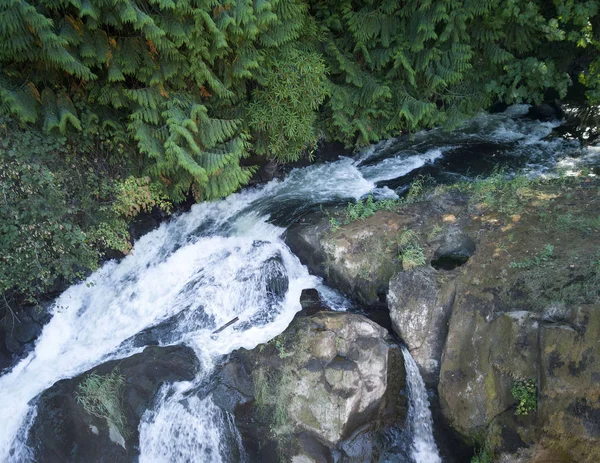 A waterfall fanning out over a rock formation at Tumwater Falls Park in Thurston County Washington state