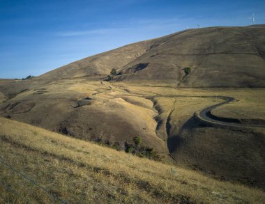 Klickitat County Washington Eyaleti yakınlarındaki Columbia Nehri 'nin sonbaharında güzel bir yel değirmeniyle dolu bir dağdaki Maryhill Döngü Yolu' nun nefes kesici manzarası.