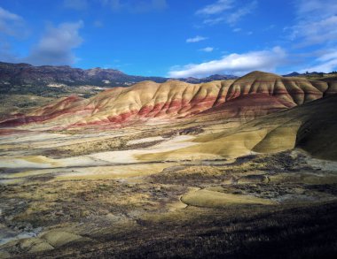 Mitchell Oregon 'daki John Day Fosil Yatakları' nda bulutlu bir sonbahar gününde kırmızı, bronzlaşmış, siyah, turuncu ve sarı çizgilerle kaplanmış renkli tepeler.