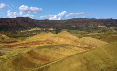 Renkli John Day Fosil Yatakları Oregon 'da yarı çöl manzarasında kırmızı yeşil turuncu ve sarı çizgili tepeleri boyadı.