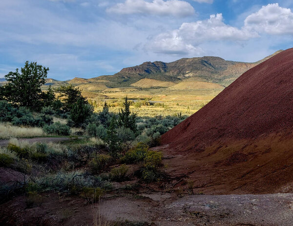 Breathtaking colorful red and white clay fossil beds with a beautiful semi desert background with big white clouds and a blue sky at the John Day Fossil Beds Painted Cove Trail in Oregon