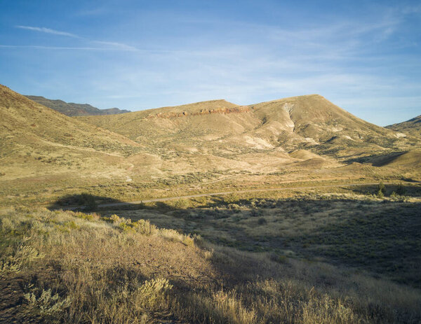 Невероятные золотые и красные холмы глиняных окаменелостей в полупустынной горной долине в солнечный день раскрашенной бухты на дне ископаемых лож в Орегоне
