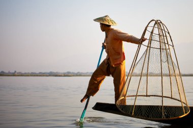 Inle Lake, Myanmar - 10 Şubat 2020: Bir Intha kayıkçısı teknesini Inle Gölü, Myanmar 'a sürmek için geleneksel bir yöntem kullanır..
