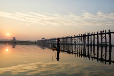 Bir balıkçı ağlarını U Bein Köprüsü, Amarapura, Myanmar 'daki göle atmaya hazırlanıyor..