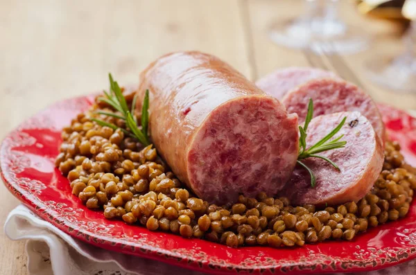 Italiaanse grote varkensworst cotechino geserveerd met linzen. — Stockfoto