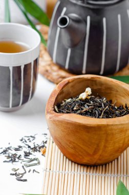 Çay fincanında yeşil çay ve bambu yapraklı beyaz masada siyah çaydanlık. .