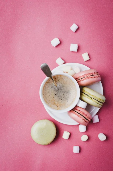 Cup of coffee and  macarons.  Colorful pink background.