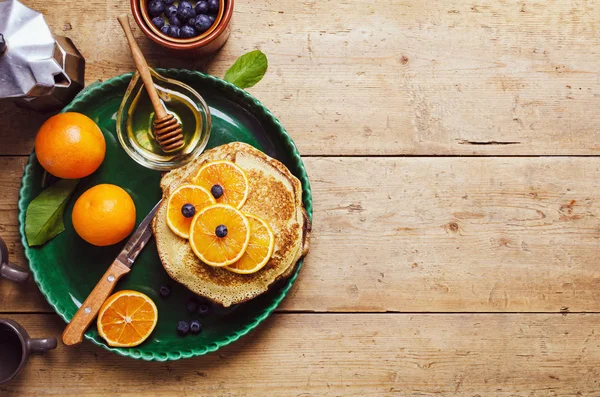 Stapel pannenkoeken met sinaasappel en bosbessen en honingsiroop. — Stockfoto